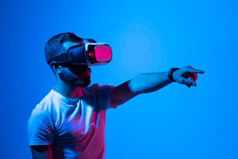男人。白色t恤穿护目镜元宇宙技术创新虚拟世界概念霓虹灯照明黑暗背景虚拟现实经验未来技术
