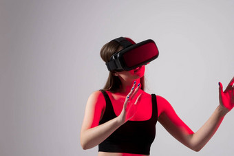 年轻的女人虚拟现实耳机<strong>触碰</strong>虚拟对象<strong>未来</strong>小工具技术教育在线研究视频游戏概念