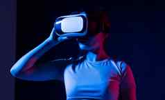 年轻的女人护目镜色彩斑斓的霓虹灯灯有趣的玩游戏朋友可穿戴虚拟增强现实