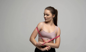 年轻的美丽的浅黑<strong>肤色</strong>的女人女人体育运动装运动服装持有粉红色的测量磁带重量损失饮食概念健康护理健康的营养<strong>完美</strong>的苗条的身体