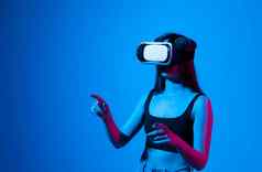 年轻的女人虚拟现实耳机霓虹灯光未来小工具元宇宙技术教育在线研究视频游戏概念