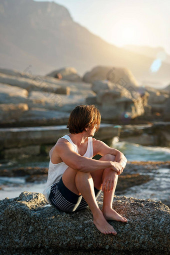 年轻的男人。坐着海滩日落看海洋考虑<strong>旅程</strong>