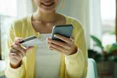 亚洲女人手持有信贷卡细胞聪明的电话
