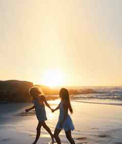 女人朋友运行海滩日落持有手有趣的夏天假期享受自由