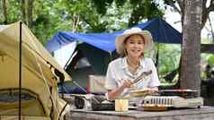 年轻的女人旅游坐着野营帐篷准备食物晚餐可移植的气体炉子旅行冒险假期概念