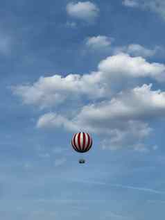 条纹热空气气球翱翔蓝色的天空背景白色云