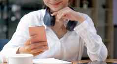 亚洲年轻的女人聪明的电话咖啡馆微笑女人智能手机首页消息传递浏览社会网络放松