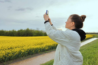 纤细的美丽的<strong>女孩</strong>芽视频黄色的油菜籽场电话<strong>女孩</strong>休息自然欣<strong>赏</strong>迷人的景观