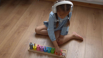快乐学前教育没有牙齿的女孩玩彩色的木玩具孩子们学习数玩教数字首页孩子听音乐大白色耳机童年教育