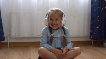 孩子听音乐大白色耳机快乐学前教育没有牙齿的女孩年相机离开房间内部孩子微笑笑着说显示舌头首页童年教育