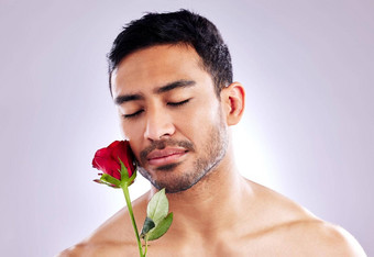 处理护理工作室拍摄英俊的年轻的男人。摆姿势红色的玫瑰
