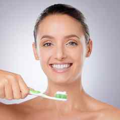 把牙科卫生美丽的年轻的女人刷牙牙齿灰色背景