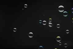 飞行肥皂泡沫黑色的背景摘要肥皂泡沫色彩斑斓的反射肥皂泡沫运动背景