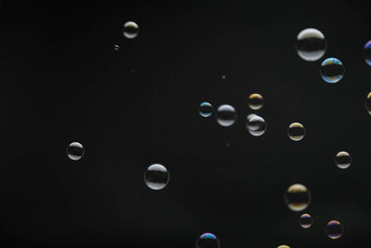 飞行肥皂泡沫黑色的背景摘要肥皂泡沫色彩斑斓的反射肥皂泡沫运动背景