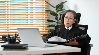 成熟的女法官律师阅读司法法律文档移动PC工作场所
