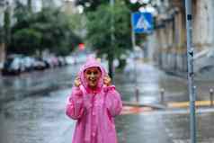 年轻的微笑女人雨衣享受多雨的一天