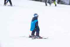 教练孩子滑雪蹒跚学步的孩子安全头盔滑雪教训年轻的孩子们冬天体育运动滑雪