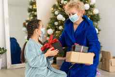 祖母（外）孙女生活房间圣诞节装饰拥抱医疗面具脸家庭假期爆发冠状病毒疾病一年
