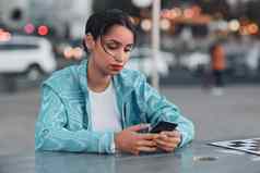 伤心抑郁强调女精神健康问题发短信电话坐着户外咖啡馆年轻的女人负响应坏新闻聊天浏览社会媒体