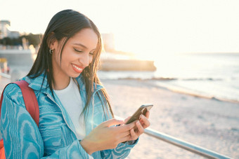 快乐女人在户外持有电话发短信搜索分享位置在线社会媒体应用程序单女享受海滩视图分享经验旅游写博客网站