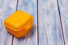 塑料黄色的午餐盒子木背景