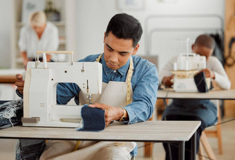 有创意的时尚设计师学习缝纫技能牛仔布衣服服装制造业工厂年轻的时尚学生缝纫机车间工作时尚的织物