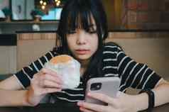 女人持有移动智能手机社会网络互联网技术吃汉堡快食物