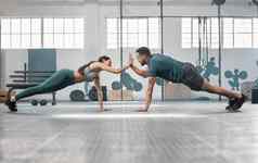 健身合作伙伴锻炼俯卧撑高健身房适合活跃的男人。女人培训健康设施部分锻炼例程夫妇锻炼