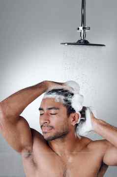 清洁头发使感觉伟大的年轻的男人。洗头发淋浴灰色背景