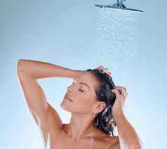 舒缓的淋浴开始一天工作室拍摄年轻的女人采取淋浴蓝色的背景