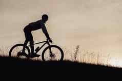 轮廓专业骑自行车的人下山自行车运动员骑下坡自行车日落