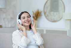 美丽的年轻的女人休息听音乐白色大耳机