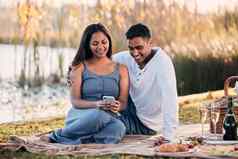 分享舒适的连接年轻的夫妇手机野餐湖边