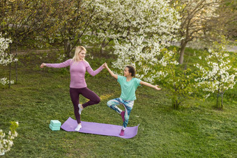 家庭妈妈。老师培训瑜伽孩子女儿瑜伽席首页花园家庭在户外父孩子花时间锻炼首页概念正常的
