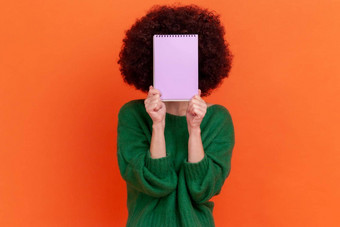 肖像未知的女人非洲式发型发型穿绿色休闲风格毛衣站持有组织者隐藏脸纸笔记本