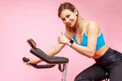 女人完美的身体体育运动练习自行车在线锻炼显示拇指
