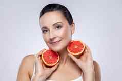 女人显示切片葡萄柚相机清洁健康的皮肤最小的化妆