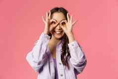 特写镜头肖像有魅力的有趣的可爱的无忧无虑的十几岁的亚洲女孩使面具手指眼睛微笑相机有趣的傻瓜玩快乐的