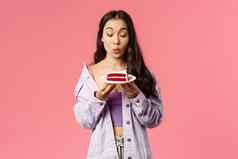 肖像兴奋逗乐年轻的漂亮的女孩急切的咬美味的甜点快乐诱惑一块蛋糕折叠嘴唇要吃粉红色的背景