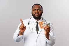 流感疾病医疗保健医学概念愤怒的严肃的表情非裔美国人医生禁止采取药片摇晃手指责骂病人药物错误的皱着眉头失望