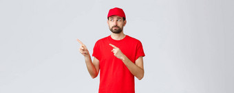 在线购物交付检疫外卖概念不确定的不高兴不情愿的快递员工红色的t恤帽得意的笑失望指出手指上左角落里