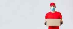 包包裹交付科维德self-quarantine交付转移订单年轻的快递红色的统一的手套脸面具持有盒子给出订单客户端非接触式服务