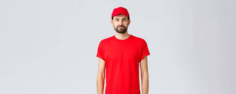 在线购物交付检疫外卖概念年轻的有胡子的快递红色的统一的员工穿帽t恤相机等<strong>待订单</strong>