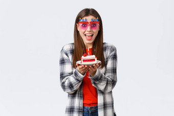人生活方式假期庆祝活动情绪概念热情的快乐生日女孩有趣的聚会，派对穿眼镜持有生日蛋糕使基斯蜡烛