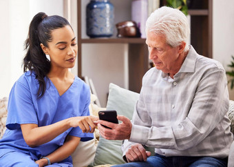 工作事情年轻的女人帮助上了年纪的病人智能手机