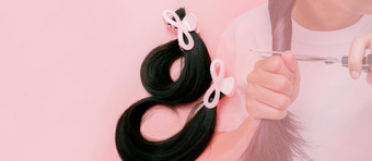 头发捐赠乳房癌症人概念捐赠头发假发乳房癌症病人捐赠癌症慈善机构亚洲女人切割长头发剪刀捐赠粉红色的背景