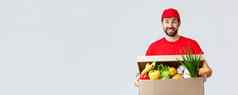 食品杂货包交付科维德检疫购物概念微笑交付男人。红色的统一的带客户端订单持有食物盒子包裹享受人转移货物