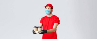 外卖食物食品杂货交付科维德非接触式订单概念愉快的快递红色的统一的脸面具手套给咖啡客户站灰色背景