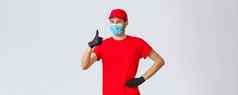 科维德self-quarantine在线购物航运概念友好的快乐的交付的家伙红色的统一的手套脸面具保证快递服务质量显示翘拇指批准