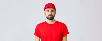 在线购物交付检疫外卖概念年轻的英俊的有胡子的快递红色的服务统一的帽t恤员工工作转让订单